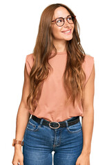 Young hispanic woman wearing casual clothes and glasses looking away to side with smile on face, natural expression. laughing confident. - obrazy, fototapety, plakaty