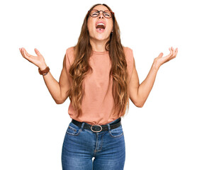 Young hispanic woman wearing casual clothes and glasses crazy and mad shouting and yelling with aggressive expression and arms raised. frustration concept.