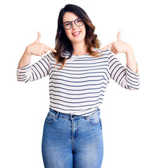 Beautiful young brunette woman wearing casual clothes and glasses looking confident with smile on...