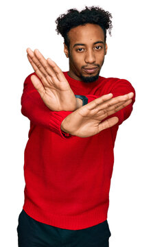 Young african american man with beard wearing casual winter sweater rejection expression crossing arms and palms doing negative sign, angry face