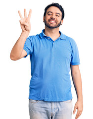Naklejka premium Young hispanic man wearing casual clothes showing and pointing up with fingers number three while smiling confident and happy.