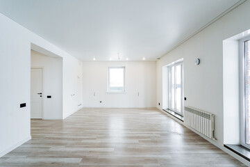 A vacant living space with hardwood floors and white walls