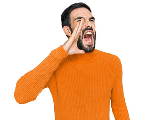 Young hispanic man wearing casual clothes shouting and screaming loud to side with hand on mouth....