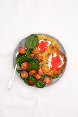 Fried potatoes pancakes with salmon caviar and cream cheese with spinach and tomatoes on white background.