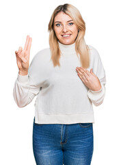 Young caucasian woman wearing casual winter sweater smiling swearing with hand on chest and fingers...