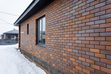 Brick building with window, snow on ground, asphalt road surface