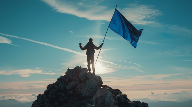 A man standing on top of a mountain holding up a blue flag with his hand