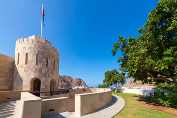The Muscat Gate Museum with the Omani flag flying on the tower at the Muttrah Gate along the walls...