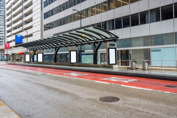 Deserted downtown bus stop with blank billboards on a rainy day. Copy space.