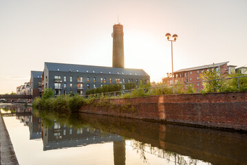 Modern apartment buildings in a redevelopment along a canal under clear sky at sunset in summer