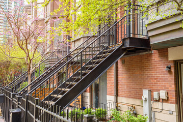 Row of metal staircases leading to the front doors of modern brick town houses on a spring day