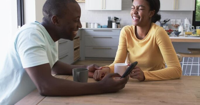 African American couple enjoys a moment in the kitchen, drinking coffee
