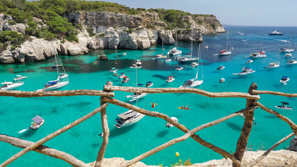 Menorca Cala Macarella panorama seen from cliff with traditional wooden fence