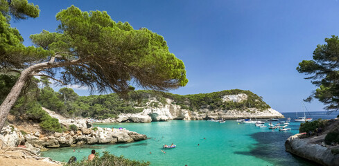 Mediterranean turquoise water surrounded by white cliffs covered by green pine trees, a picturesque...