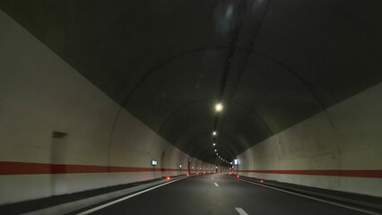 Windscreen front view POV of driving car in long underground tunnel