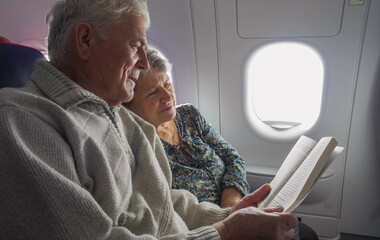 Seniors couple reading a book in the airplane