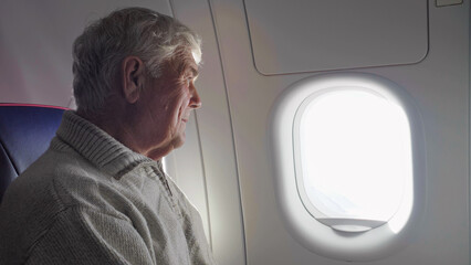 Single old man watching on window in the airplane