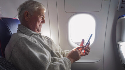 Old man watching the mobile phone in airplane