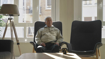 Single elderly man taking a nap in the armchair at home - obrazy, fototapety, plakaty