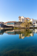 Calm river reflects old Trebinje town with Sahat Kula tower and museum building in clear blue...