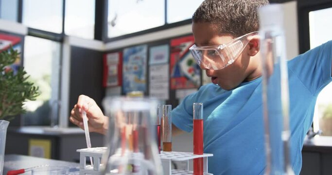 In a school classroom, a young African American student conducts an experiment