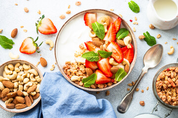 Yogurt with granola and strawberries on white. Healthy snack or breakfast, fruit salad. Top view.