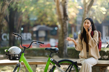 Beautiful woman taking a bike stroll in the park, business woman holding smartphone using bike rental, business woman holding smartphone using bike rental digital phone.