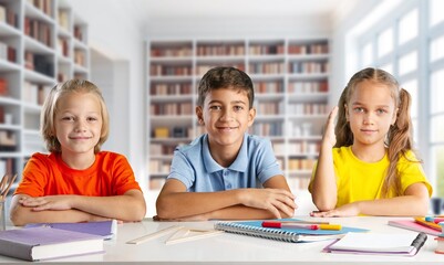 Fototapeta premium School children study together in the library with books