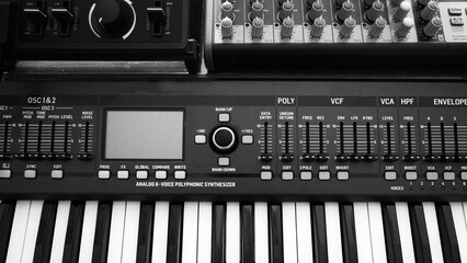 Close-up of a combination of several electronic analog synthesizers in black and white