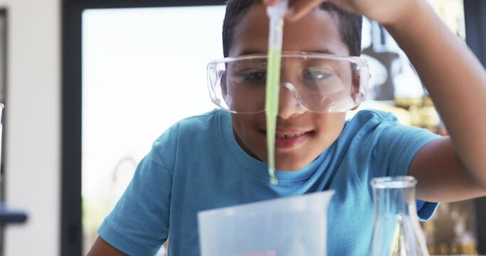 In a school science lab classroom, a young African American student conducts an experiment
