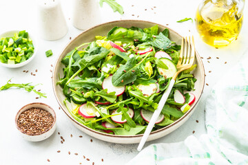 Green salad with spinach, arugula, radish with olive oil and seeds.