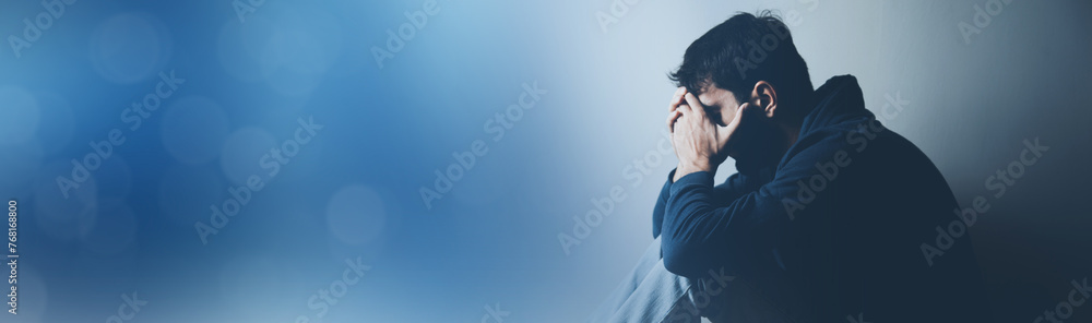 Poster sad man sitting on ground on dark background