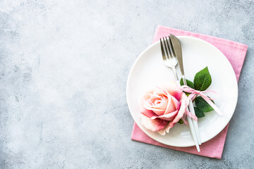 Spring Table setting with white plate and rose flowers. Table decor for an anniversary or wedding.