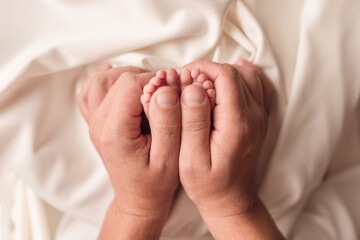 Baby feet of a newborn in dad's hands. On a white background.