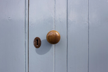 Copper gold door knob and keyhole against grey painted door with texture lines and ridges
