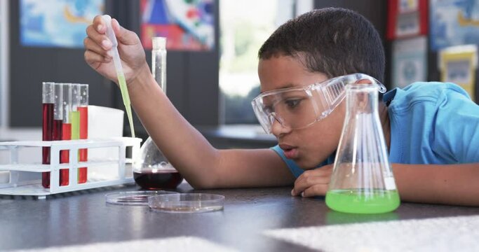 In a school setting, in a classroom, a young African American student examines a chemical reaction