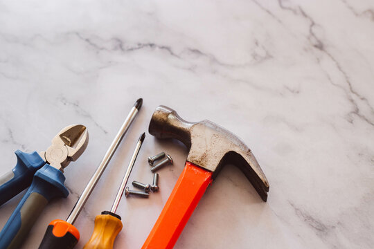 Destornillador, martillo, clavos, tornillos sobre un fondo de marmol 