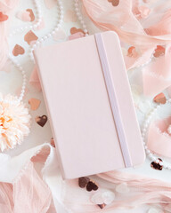 Pink hardcover notebook near hearts and romantic pink decor top view, textbook mockup