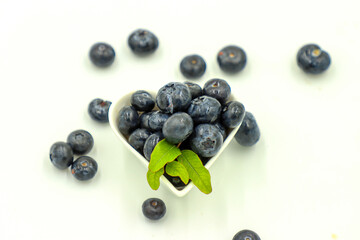Fresh organic blueberries in a heart bowl closeup view on white background
