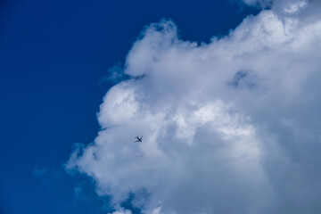 The passenger airplane is flying far away in the blue sky and white clouds. - 768178647