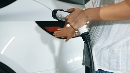 Young motion woman travel with EV electric car to shopping center parking lot charging station in...