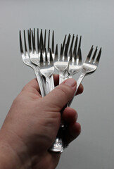 Bunch Of Different Size Silvery Forks In Cook Fist On White Background Vertical Stock Photo
