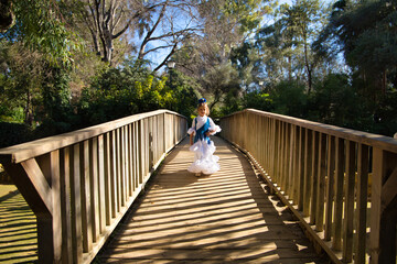 A pretty girl dancing flamenco in a typical gypsy dress with frills and fringes walks on a wooden...