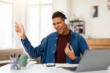 Black teen boy enjoying music, singing, imaging playing guitar