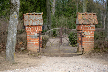 old cemetery gate with pylons made of red bricks. Lielplatones kapi, Latvia.