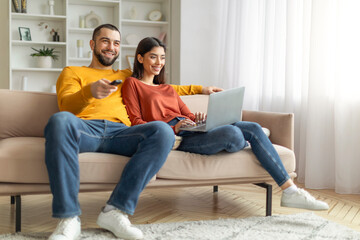 Couple relaxing on couch with laptop and remote