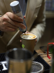 Fototapeta na wymiar barista decorating cappuccino with cream