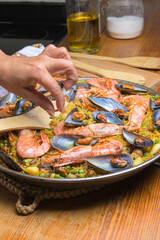 A hand serving seafood paella with prawns and mussels using a wooden spatula, typical Spanish cuisine, Majorca, Balearic Islands, Spain