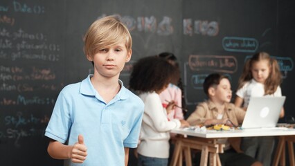 Smart boy showing thumb while diverse friend working or learning engineering code or prompt in STEM...