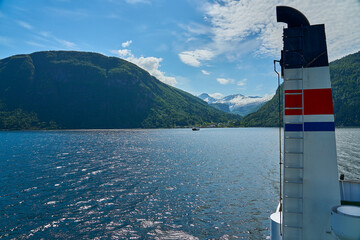 typical norwegian car ferry crossing a beautiful fjord between the mountains transporting...